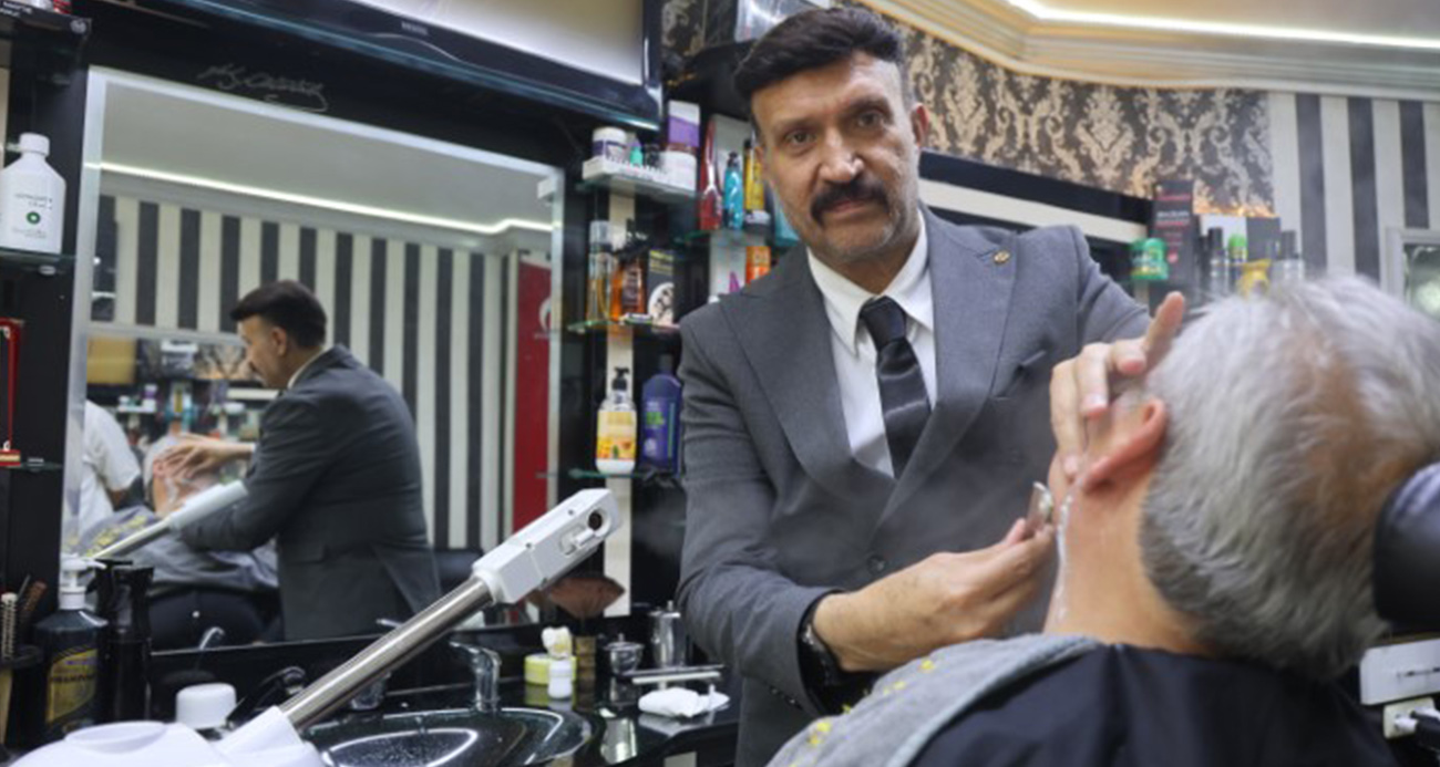 Müşterilerini takım elbiseyle tıraş ediyor